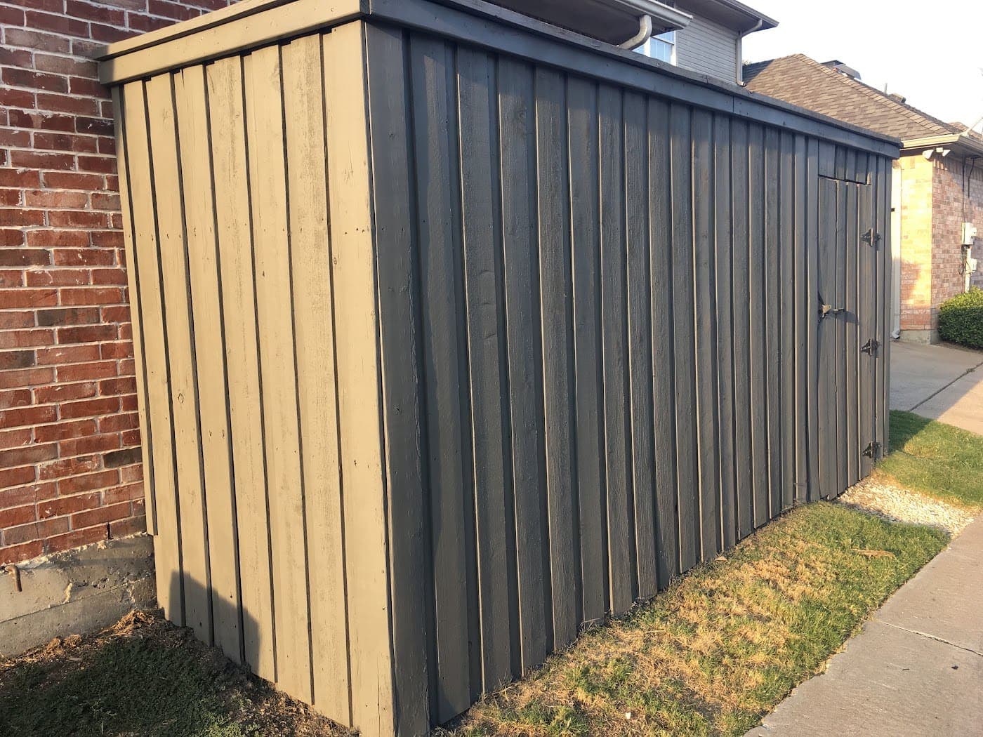 Custom cedar board-and-batten enclosure screening equipment beside a house