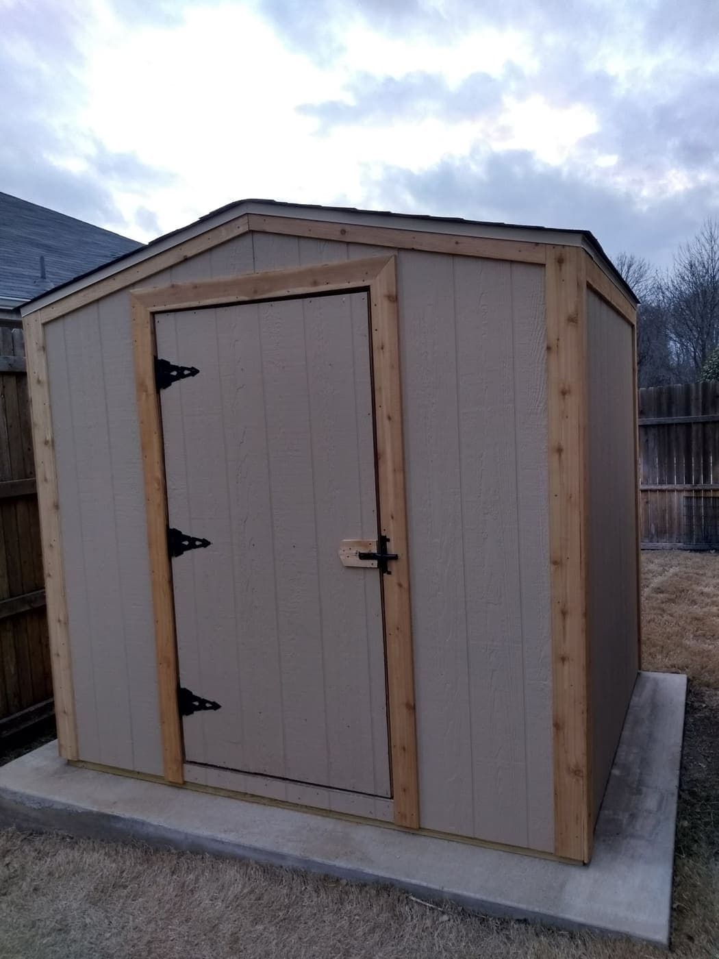 Storage shed finished with cedar trim and a black-hardware door