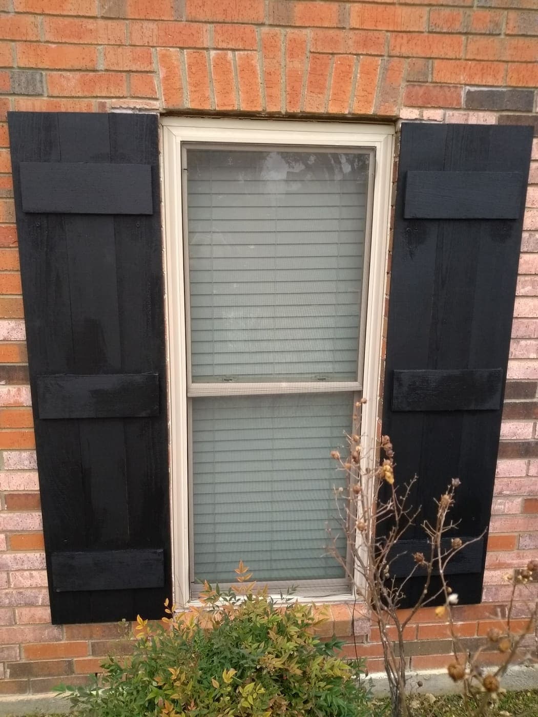 Board-and-batten wood shutters built for a brick home