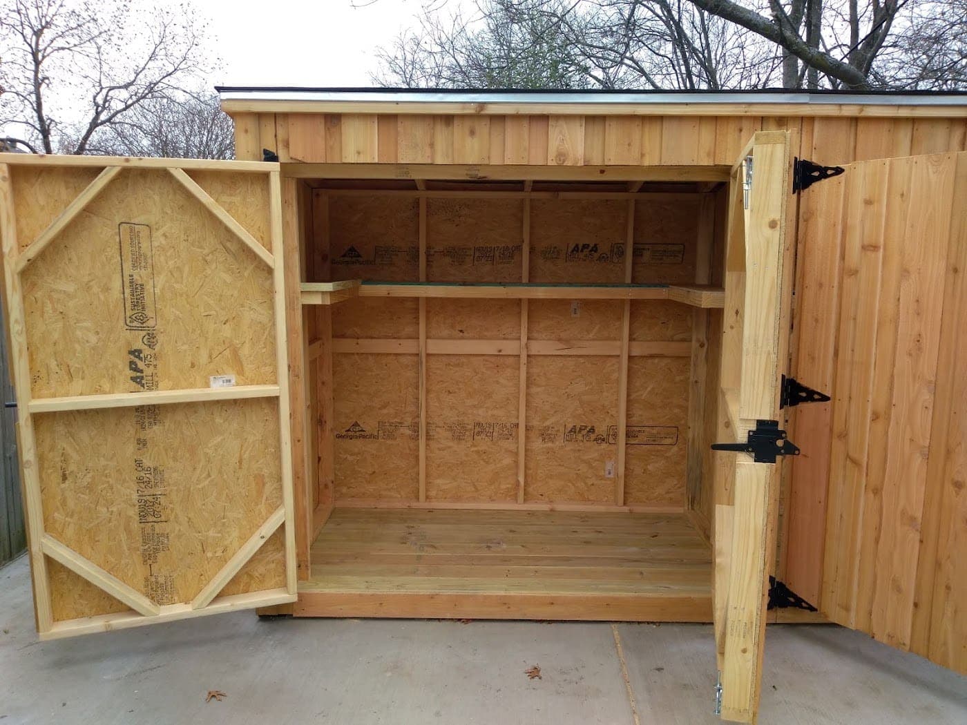 Cedar storage shed opened to show the built-in shelving