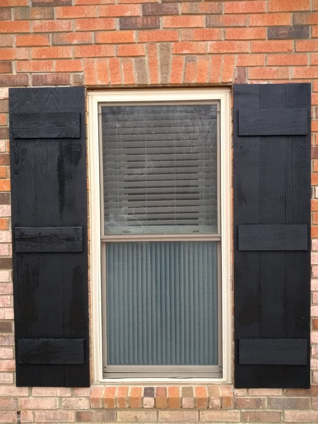 Black board-and-batten shutters framing a window