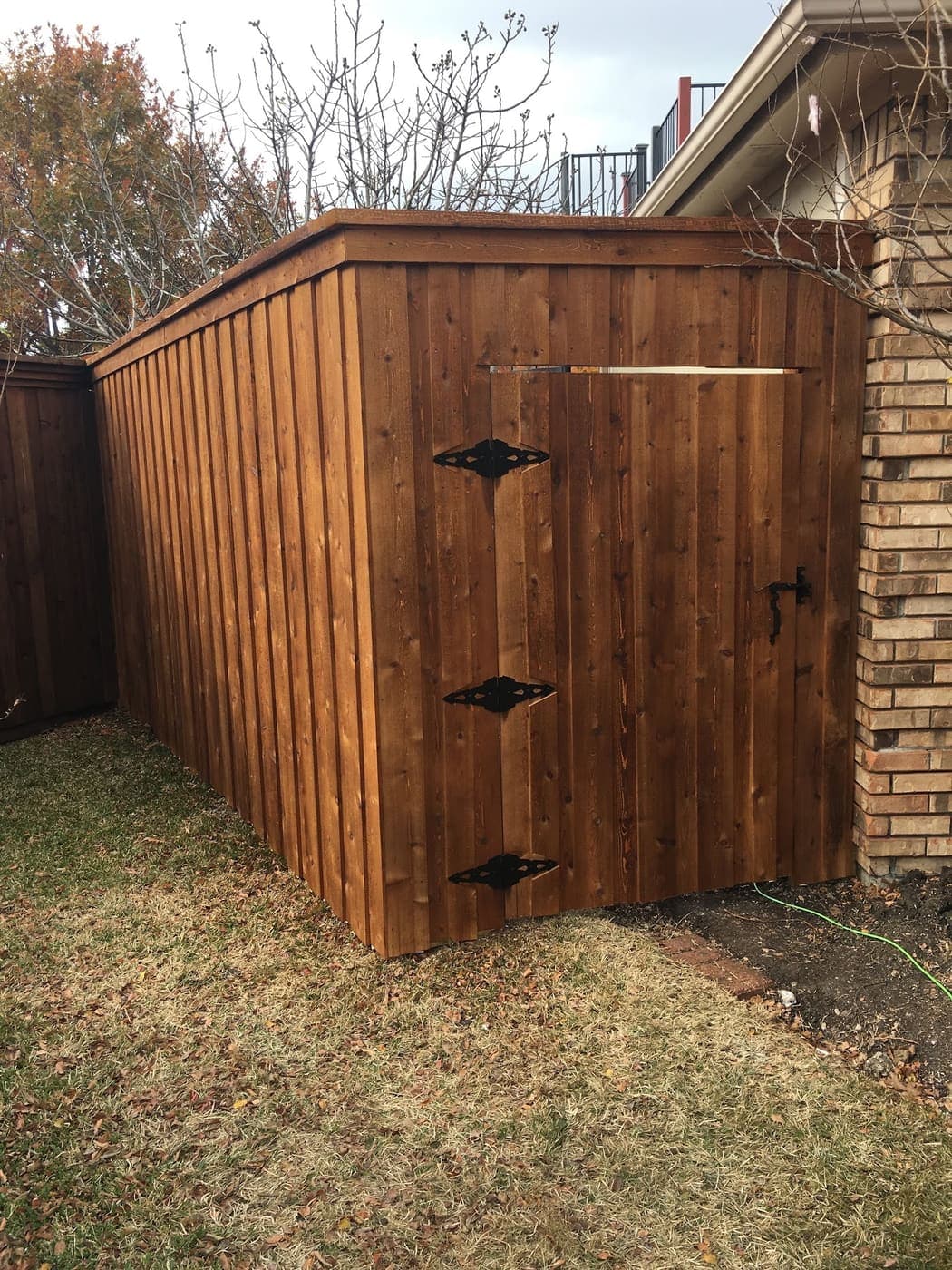 Custom cedar enclosure with a black-hinged access gate