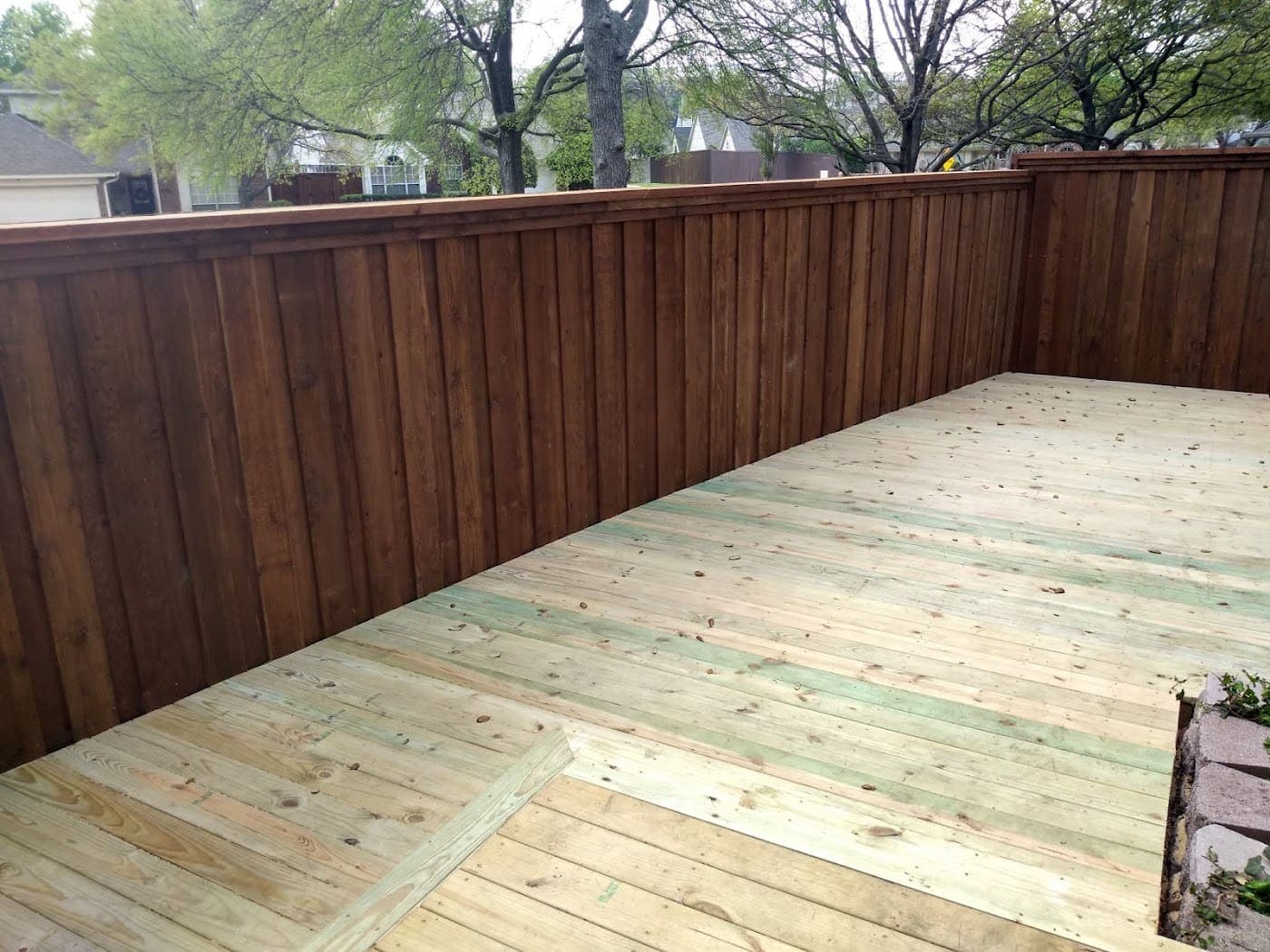 Ground-level deck built against a new cedar fence