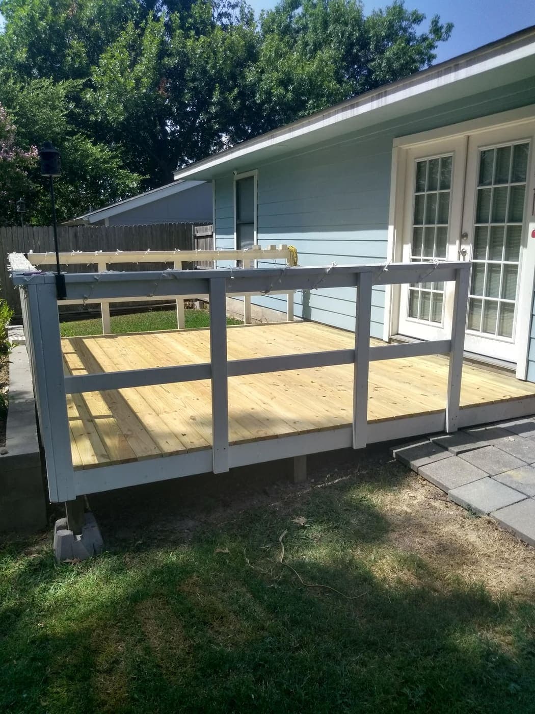 Deck with painted railing attached to the back of a house