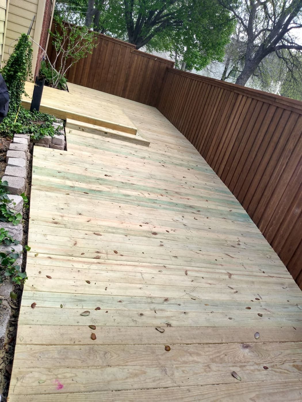 Deck walkway laid along a stained cedar fence line