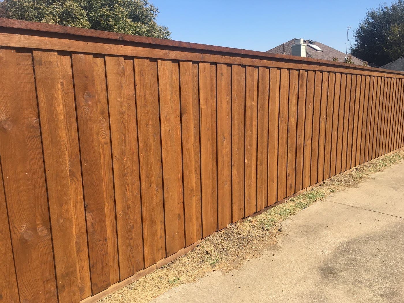 Stained cedar privacy fence run behind a DFW home
