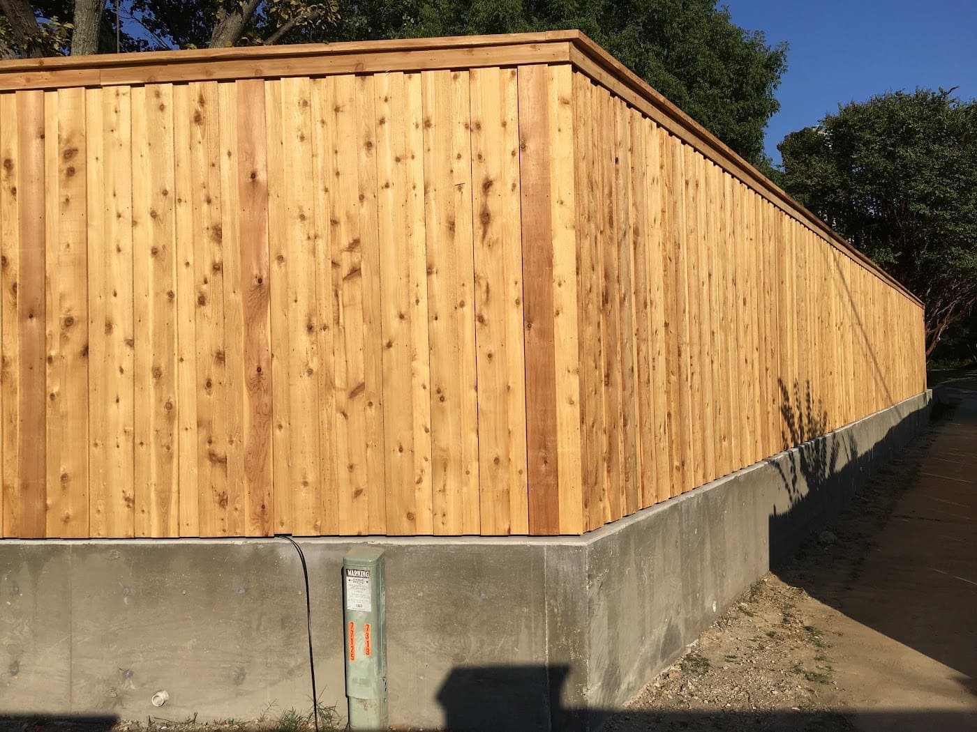 Cedar board-on-board fence stepped down a sloping grade