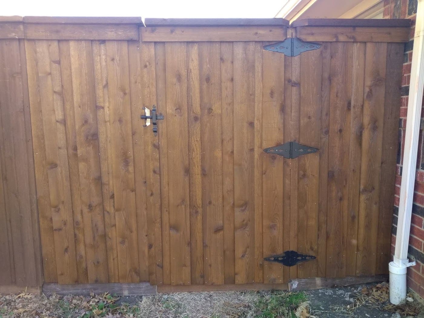 Cedar gate with three black hinges hung square in its opening