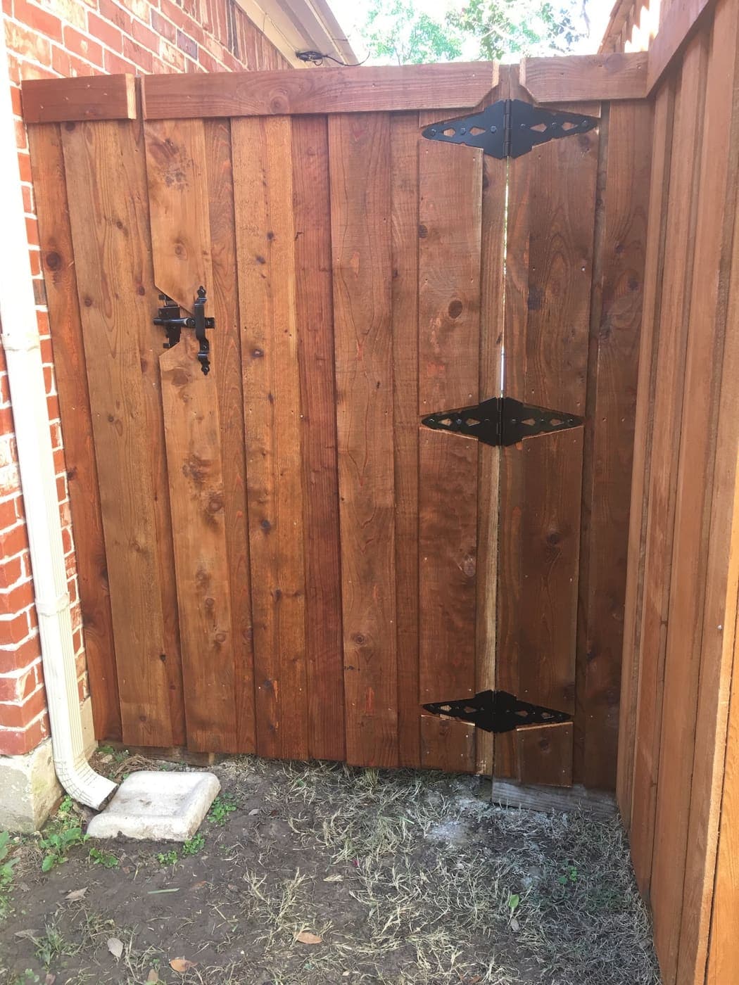 Cedar gate against brick with black hardware