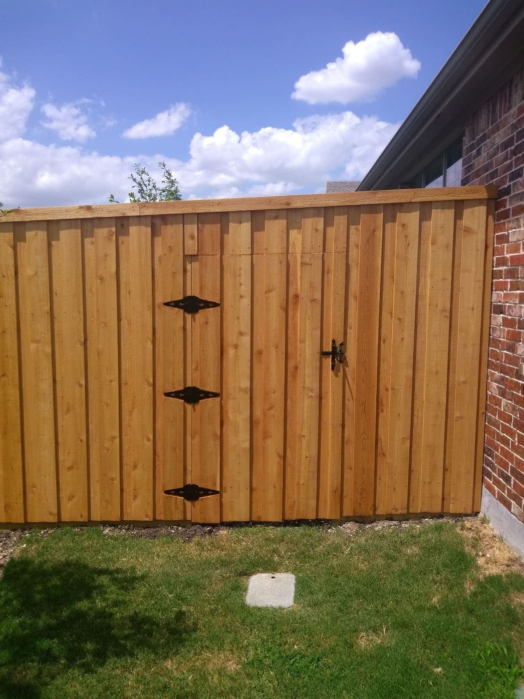 Cedar gate with black hardware in a stained privacy fence