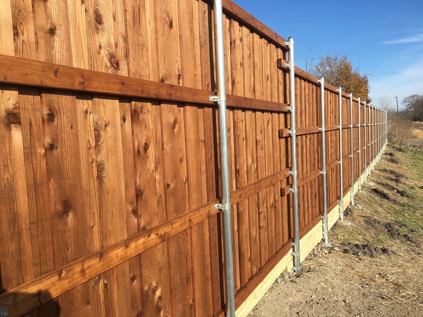 Board-on-board cedar fence mid-install on steel posts