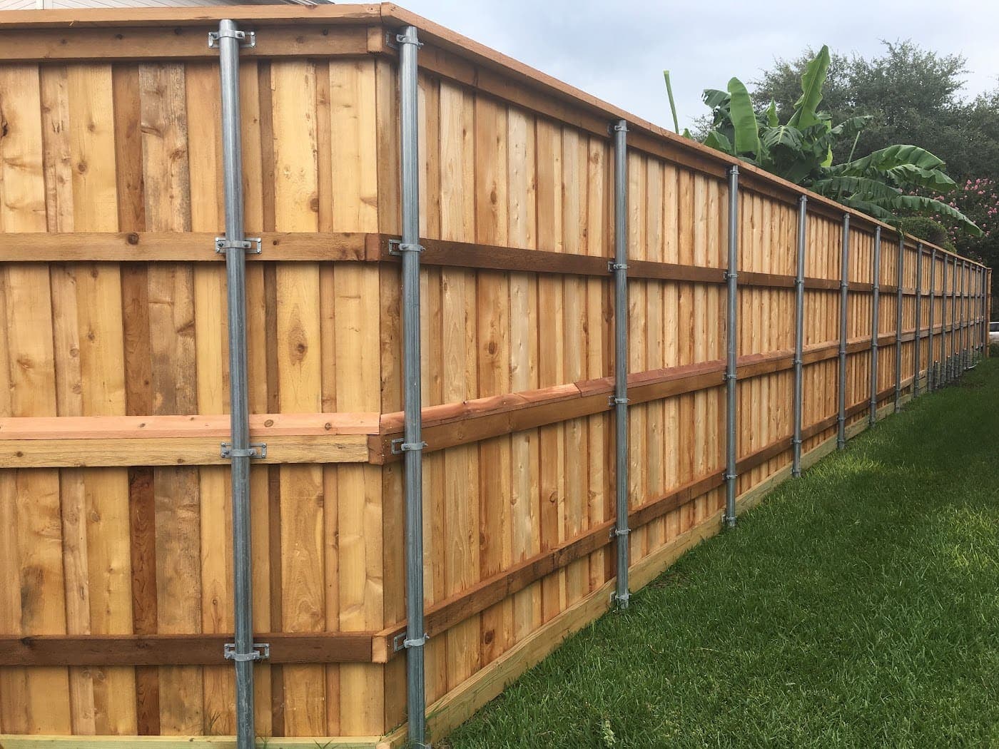 Cedar fence install in progress on 13-gauge steel posts