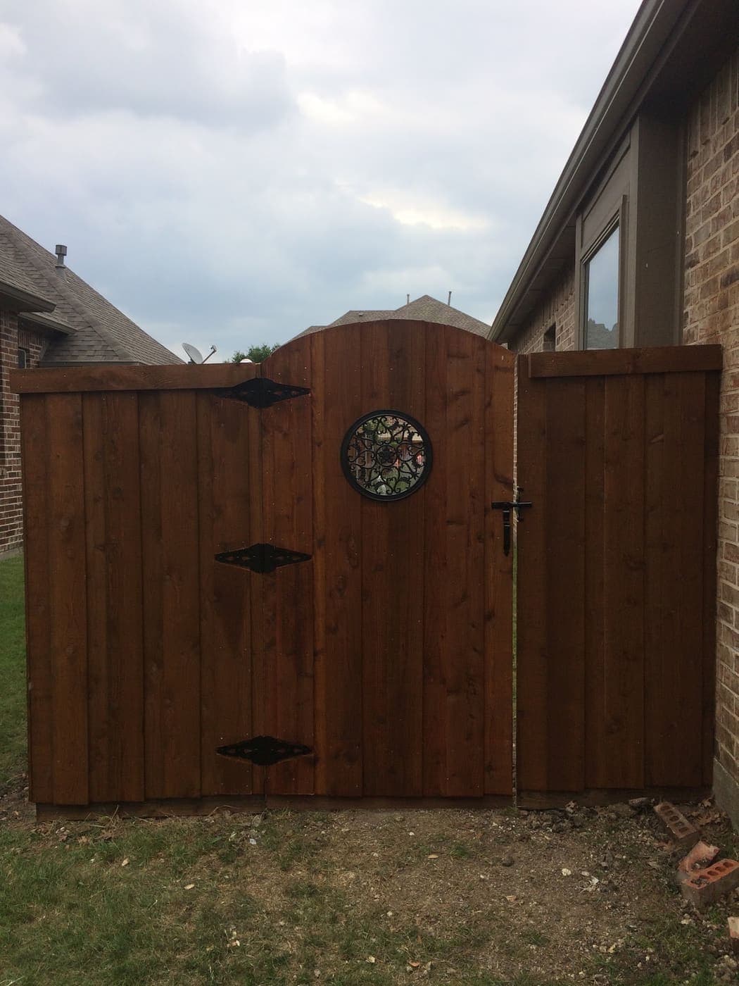 Arched cedar gate with stained glass insert and black hinges