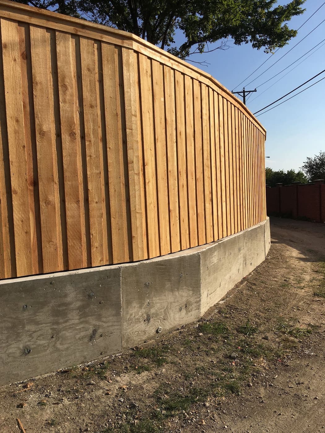 Cedar fence curving along the top of a retaining wall
