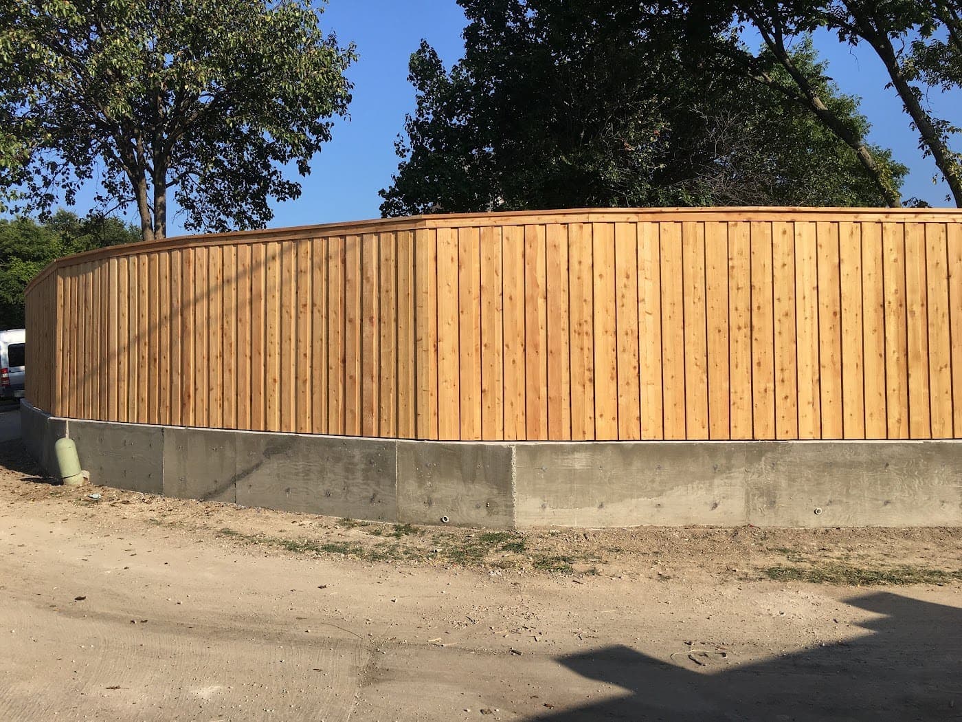 Cedar fence following a curved retaining wall