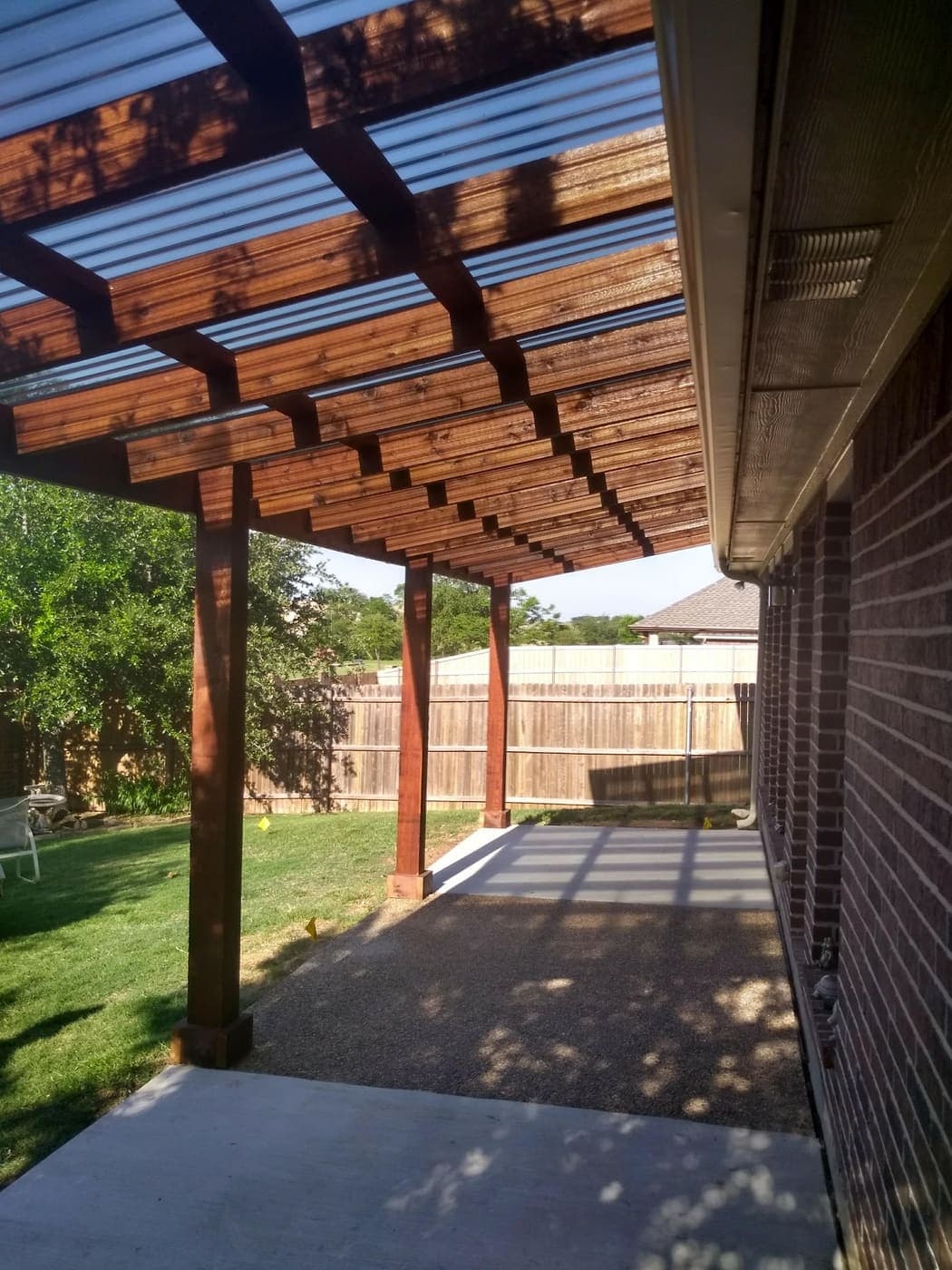 Attached patio cover with roof panels over a covered walkway