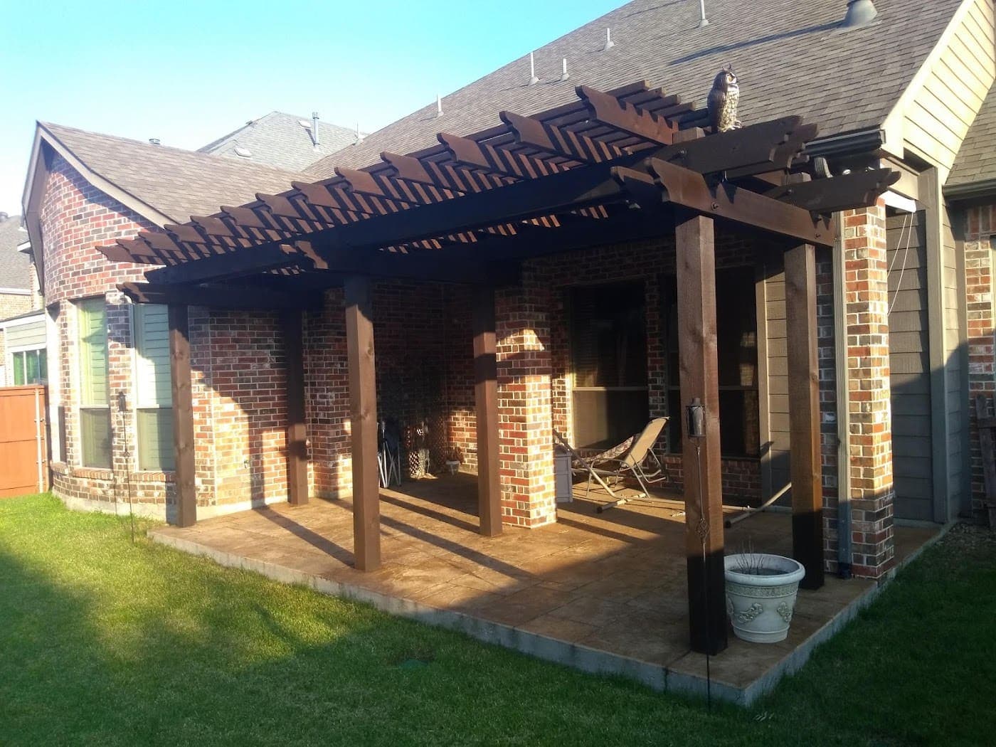 Large cedar pergola over a brick patio with masonry columns